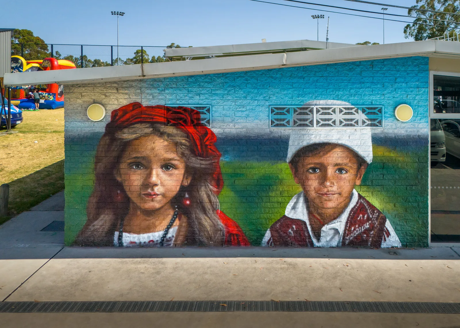 Ein Wandbild zweier albanischer Jugendlicher in Tracht an einem Gebäude am George Andrews Reserve, Dandenong