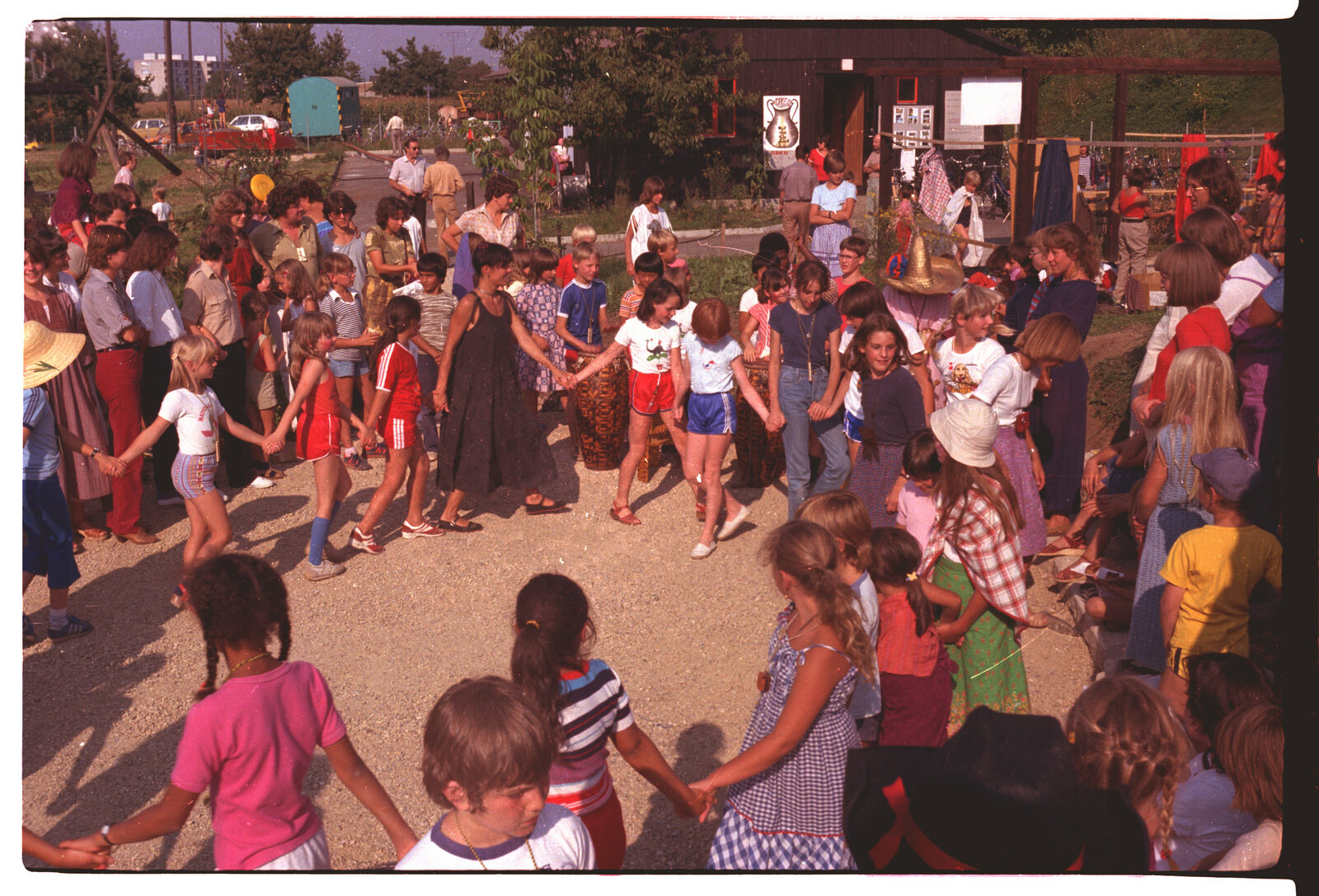 A large ring of children and adults holding hands and dancing at a neighbourhood festival on the Laengi estate in Pratteln
