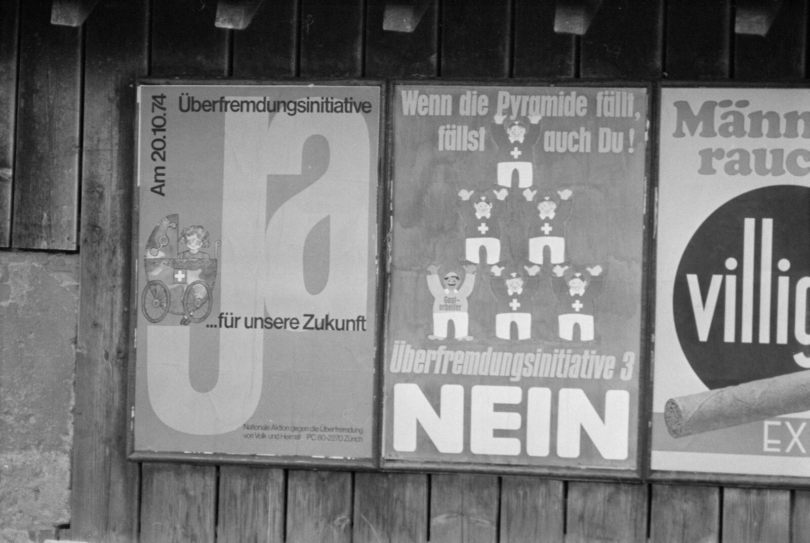 Two rival campaign posters for the third Ueberfremdung initiative pasted side by side on a wooden hoarding in Basel