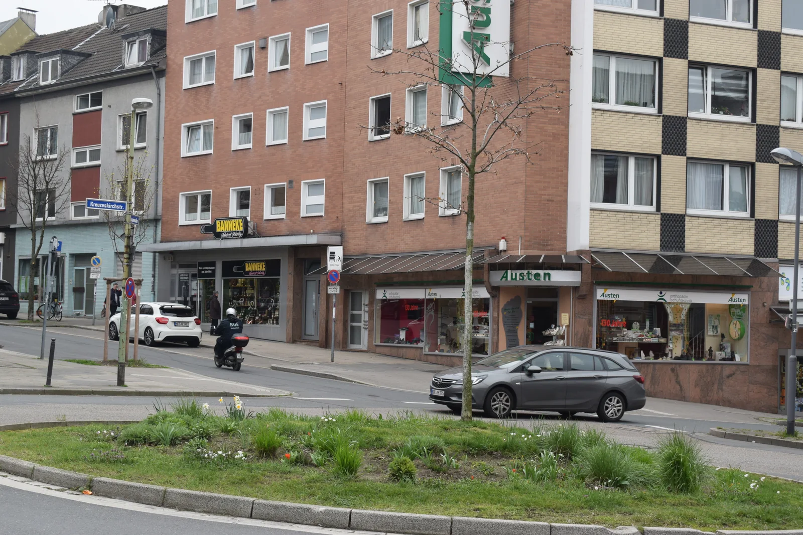 Geschäfte, Wohnungen und vorbeifahrender Verkehr an der Kreuzeskirchstraße in der Essener Innenstadt.