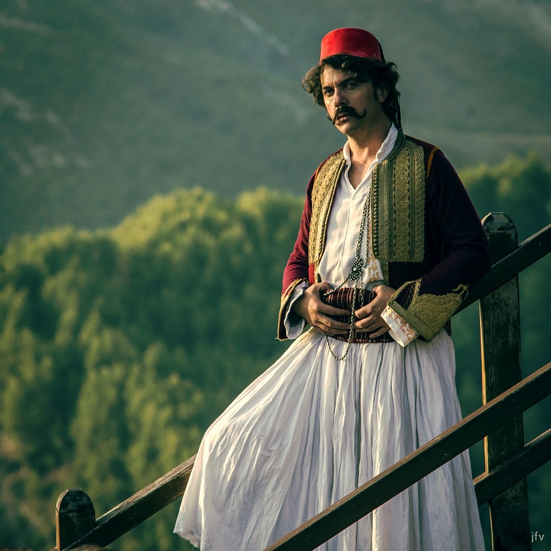 Laert Vasili in traditioneller Fustanella-Tracht vor Bergkulisse