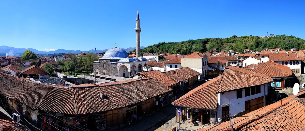 Gjakova'daki Büyük Çarşı'nın kiremitli çatıları yukarıdan görünüyor; aralarında Hadum Camii'nin kubbesi ve minaresi yükseliyor