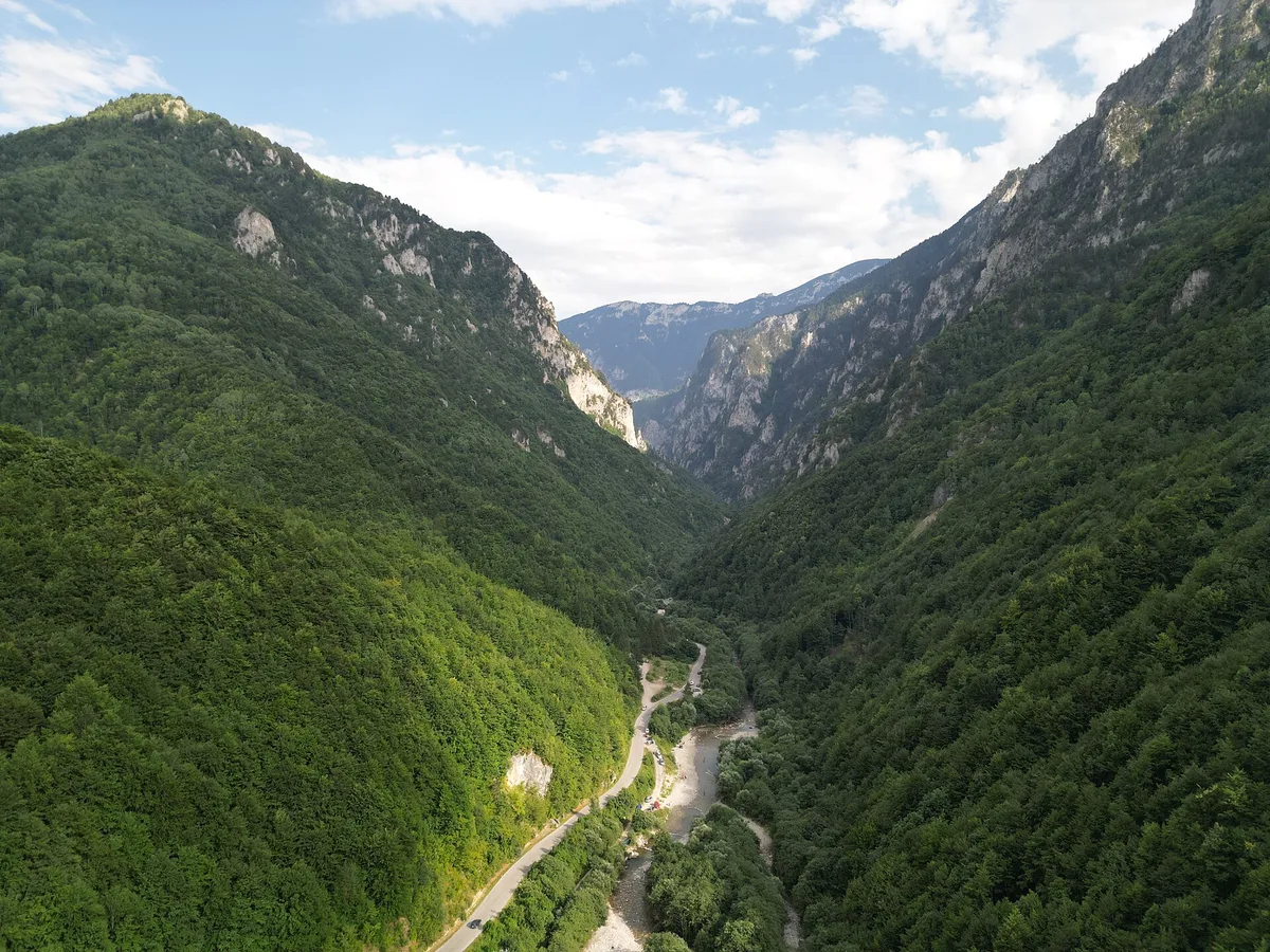 Peja'nın üzerindeki Rugova Boğazı havadan görünüyor; ormanlık yamaçlar vadi tabanındaki yola ve nehre iniyor, kaya duvarları yüksek zirvelere doğru açılıyor
