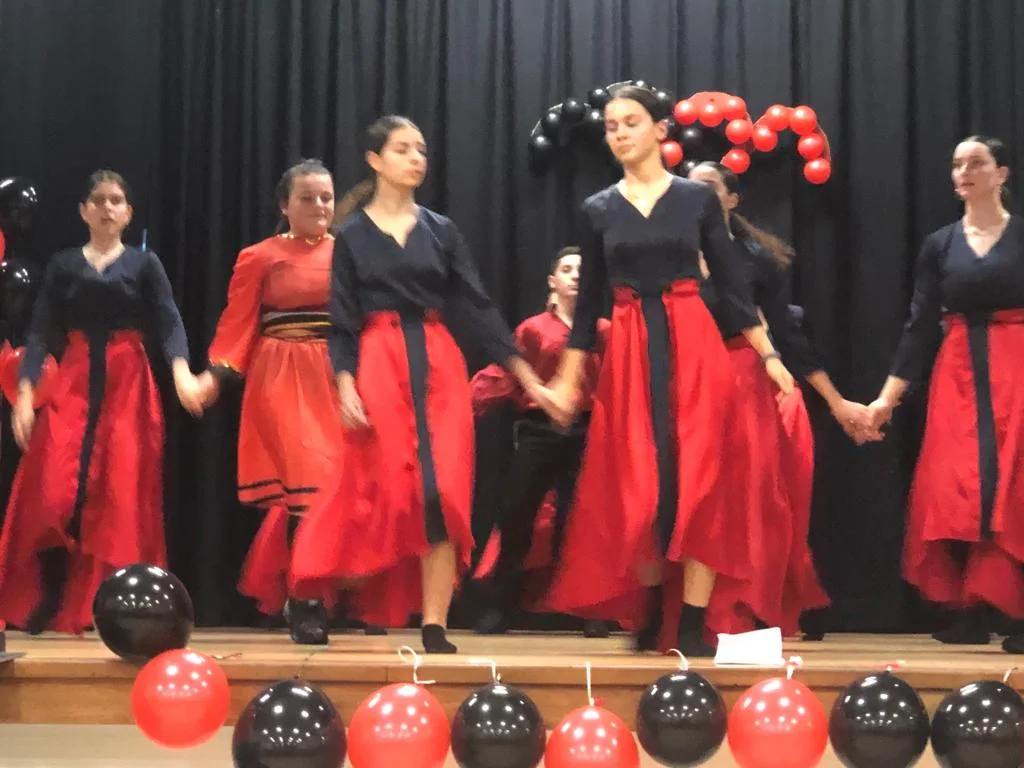 Valltarë të rinj shqiptarë me kostume të kuqe dhe të zeza duke performuar në një festim të Programit Shpresa Flag Day në Londër
