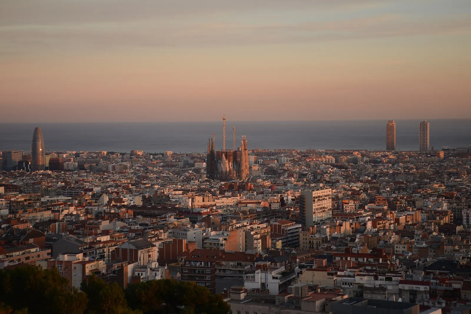 Barcelona vom Park Güell aus gesehen, mit der Sagrada Família und dem Raster des Eixample, das sich bis zum Meer erstreckt
