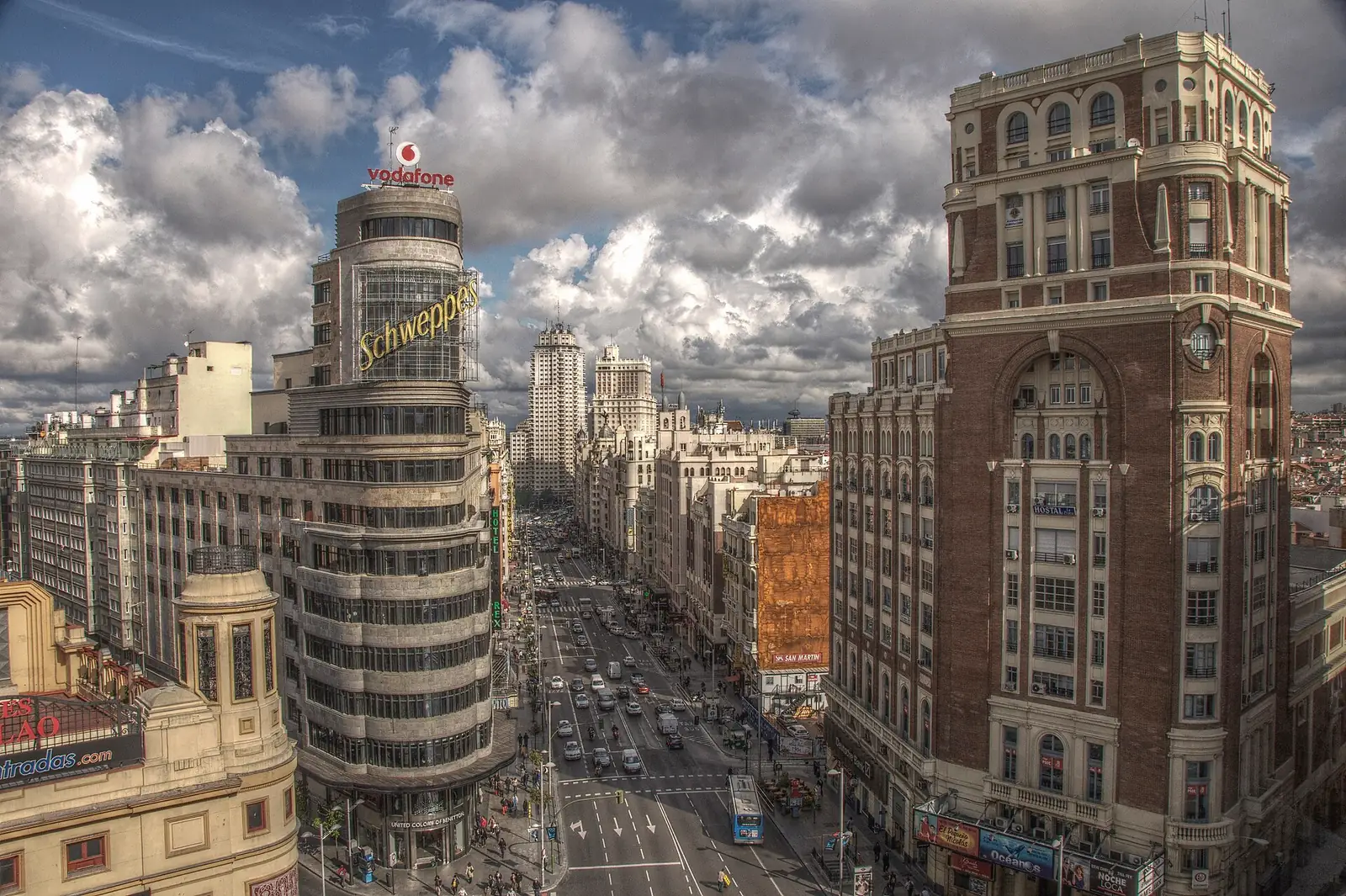 Die Gran Via in Madrid von oben an der Kreuzung Callao, mit dem Carrion-Gebäude und dichtem Verkehr unter dramatischem Himmel