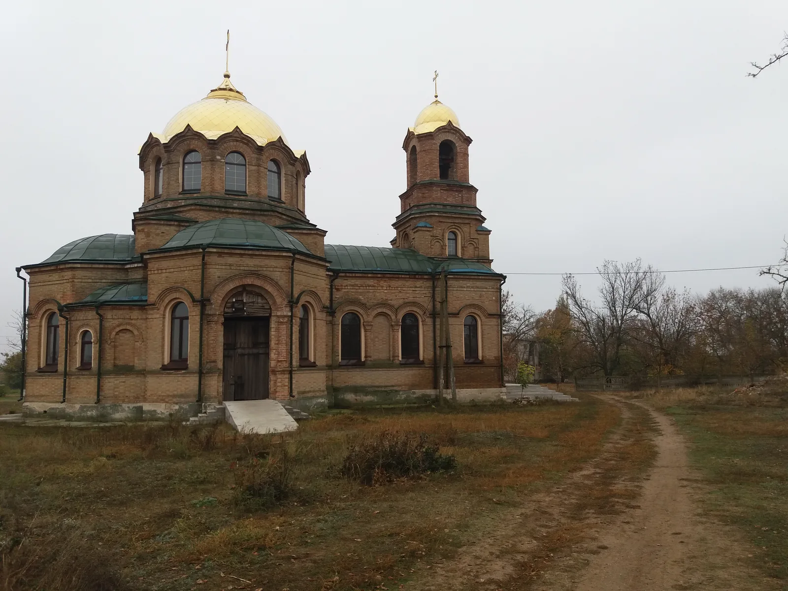 Die Backsteinkirche des heiligen Elias in Diwnynske mit goldener Kuppel an einem bedeckten Tag