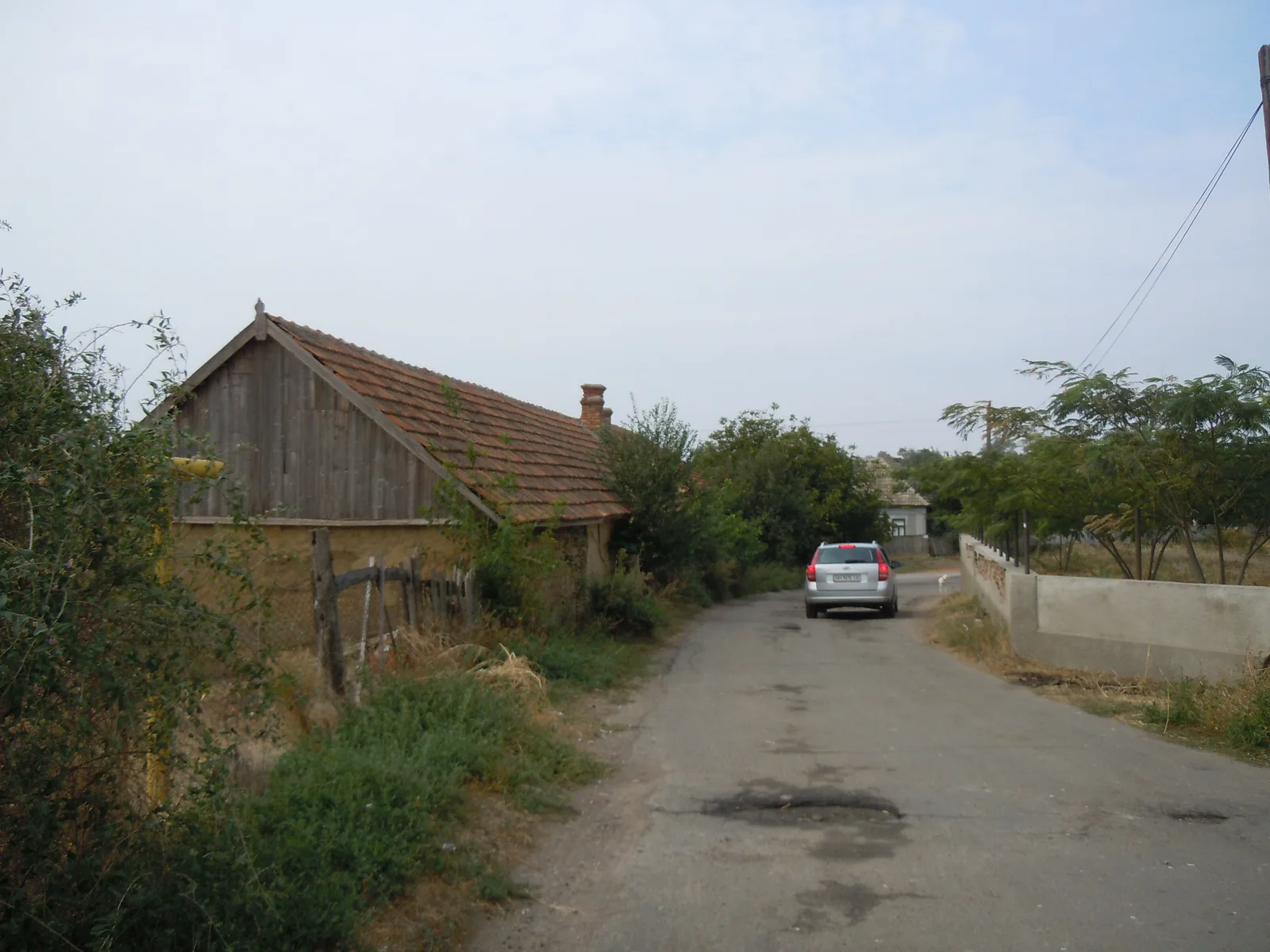 Ein von Erde gesäumter Weg in Karakurt mit einer alten Scheune aus Holz und Lehm unter einem Ziegeldach