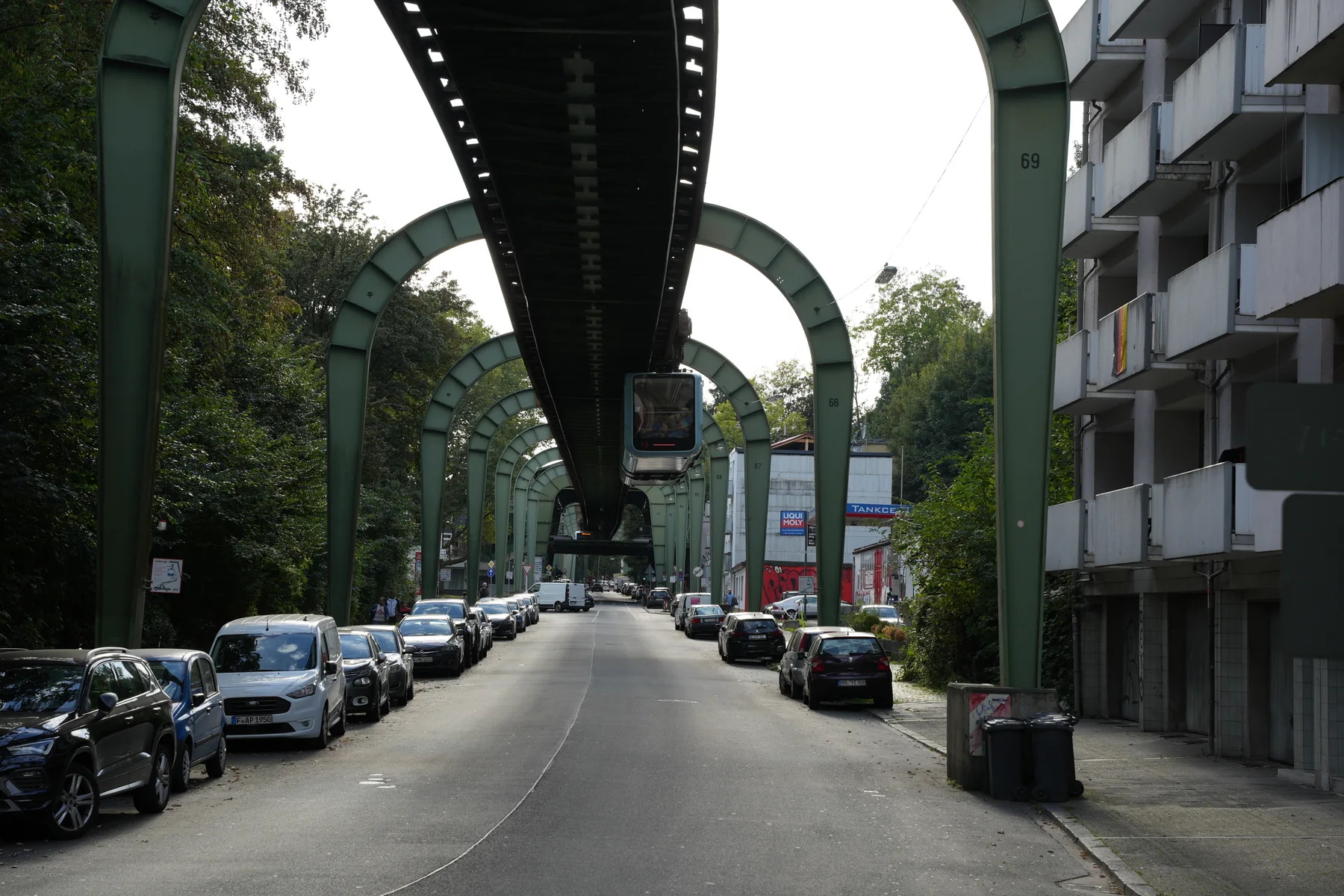 Wuppertal street beneath the steel structure of the Schwebebahn, with a train overhead