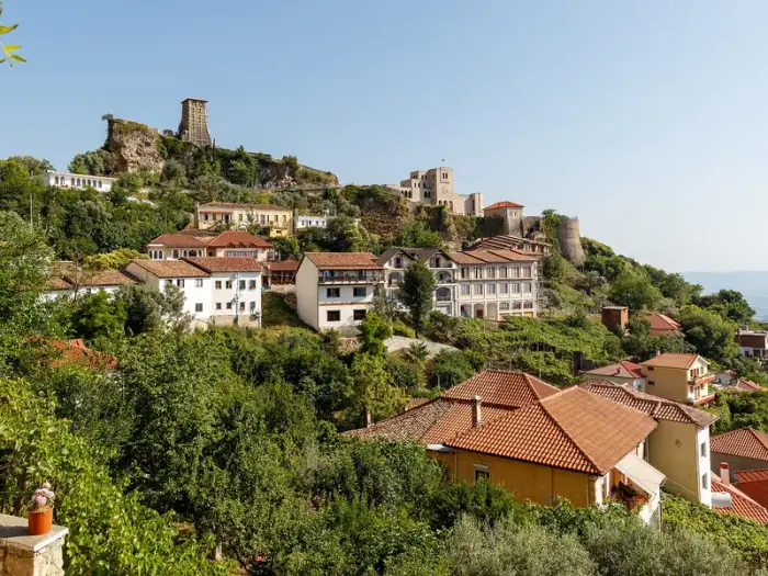 Las casas de tejados rojos de Krujë ascienden por una ladera verde hacia la roca del castillo