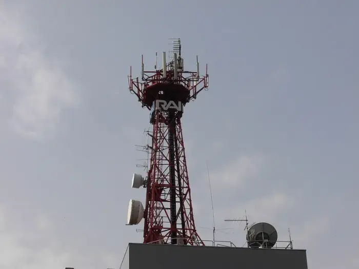 Mástil emisor de celosía roja con grandes letras RAI en el edificio regional de Rai en Cosenza