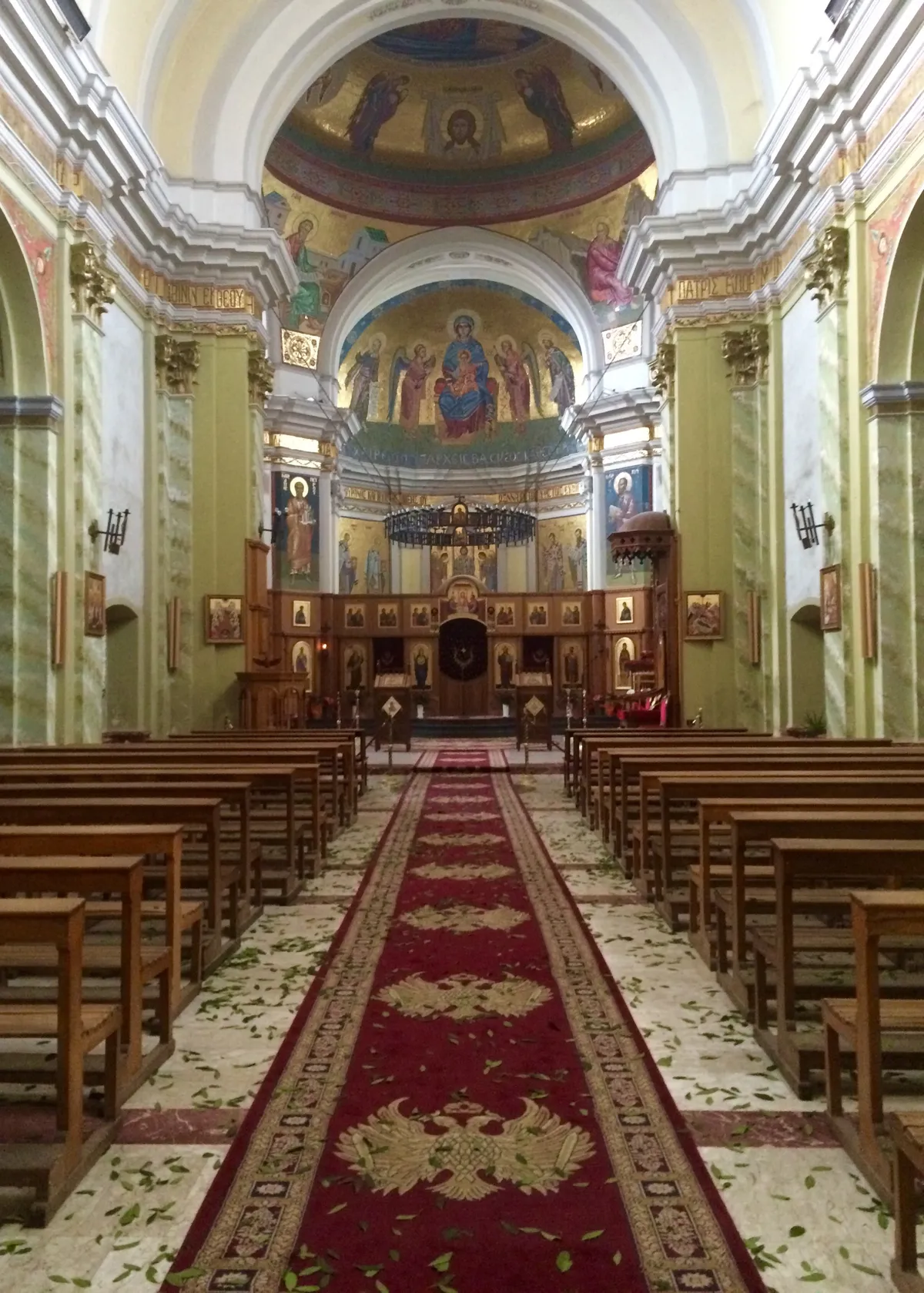 Hojas de laurel esparcidas por la alfombra roja de la nave de la catedral de Lungro, hacia el iconostasio