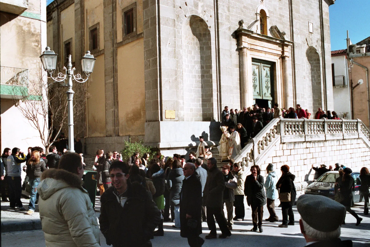 Clérigos con vestiduras doradas y un obispo con báculo encabezan una procesión que baja por las escaleras de la catedral de Piana degli Albanesi